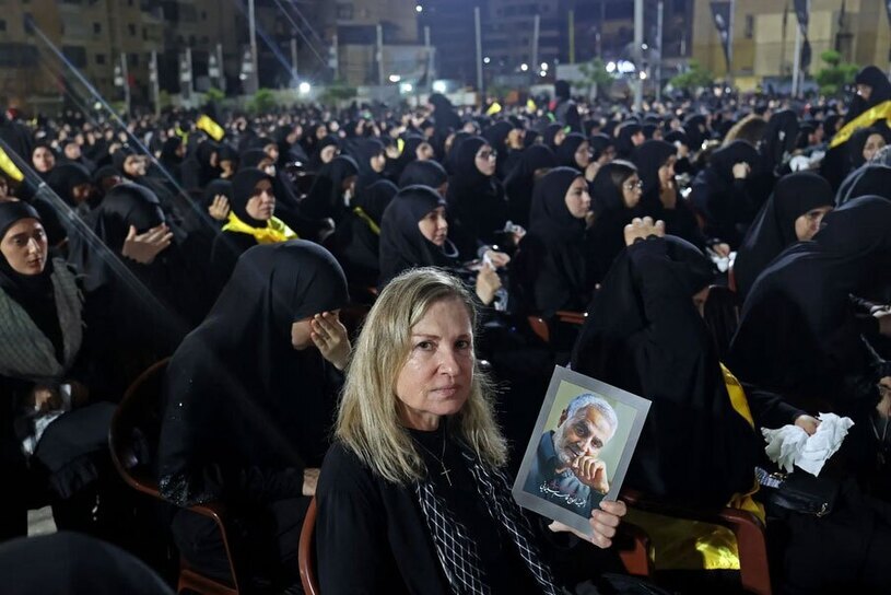 عکس / یک زن بدون حجاب با تصویری از شهید سلیمانی در مراسم عزاداری محرم