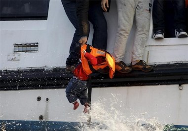  پناهنده‌ای سعی دارد کودکش را به یکی از نجات غریق‌های داوطلب در جزیره لسبوس یونان بدهد.