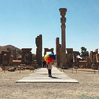 بازدیدکننده‌ای با چتری برای محافظت در برابر آفتاب در تخت جمشید، پایتخت تشریفاتیِ امپراطوری هخامنشیان. عکس از صنم جوادی