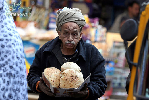 مرد مصری پس از خرید نان در حال عبور از بازار سبزی قاهره