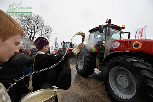یک کشیش ارتدوکس در حال متبرک کردن تراکتور در جریان برگزاری مسابقه تراکتور در بلاروس
