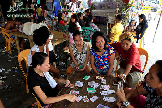 ورق بازی بستگان در کنار تابوت دو اعدام شده در عملیات مبارزه با مواد مخدر در فیلیپین