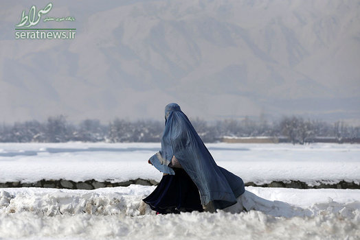 یک زن افغان در حال پیاده روی بر روی برفهای شهر کابل
