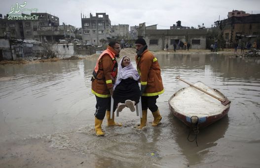 کمک به یک زن فلسطینی گرفتار در سیلاب ناشی از بارش شدید باران در اردوگاه پناهندگان شمال غزه