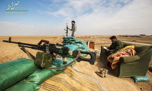 دو رزمنده الحشد الشعبی یکی در حال قرائت قرآن و دیگر در حال نگهبانی در نزدیکی روستایی در حومه تلعفر - غرب موصل