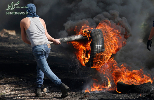 جوان فلسطینی با لاستیک آتش زده در جریان درگیری با نظامیان اسرائیلی در روستای کفرقدوم