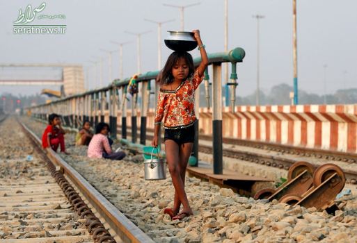دختر هندی در حال حمل آب در سطل و قابلمه در حومه اگرتلا