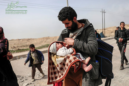 یک مرد عراقی با نوزادش در حال فرار از درگیری ها در غرب موصل