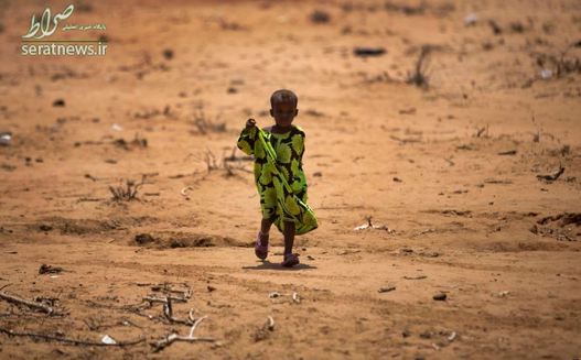 کودک اتیوپیایی در حال راه رفتن زیر نور افتاب در یک روستای قحطی زده
