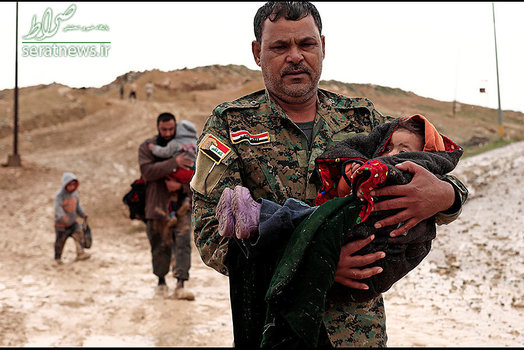 یک عضو الحشد الشعبی کودکی را در غرب موصل در آغوش گرفته