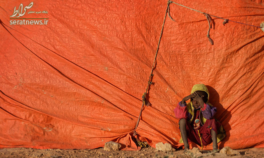 پسربچه سومالیایی نشسته در کنار یک چادر آوارگان کمی پس از طلوع خورشید