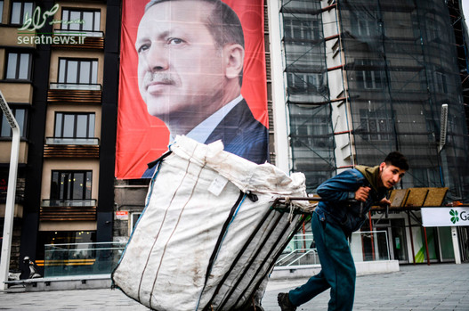 یک مرد زباله جمع کن در حال عبور از مقابل پرتره بزرگ رجب طیب اردوغان رییس جمهور استانبول در میدان تقسیم استانبول