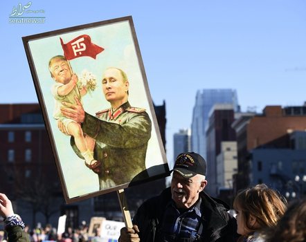 یک معترض با عکسی در دست که در آن ترامپ همچون بچه ها در دست ولادیمیر پوتین رییس جمهور روسیه است