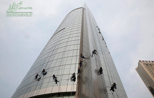 شیشه پاکن ها در حال تمیز کردن نمای یک آسمان خراش در پکن