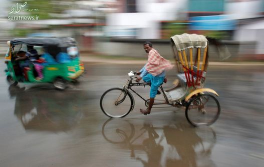 مردی با دوچرخه کالسکه ای در هوای بارانی اگرتلای هند