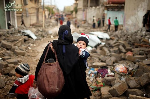 نوزاد عراقی با مادرش در حال ترک خانه خود در غرب موصل