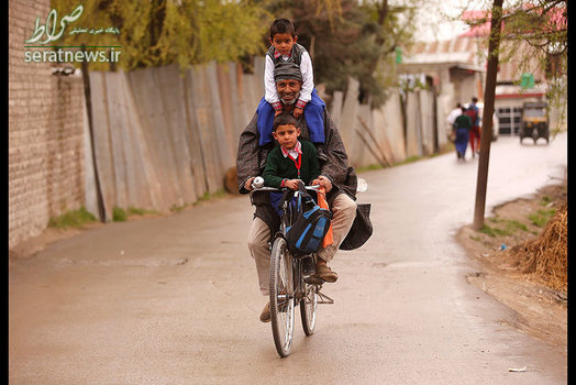 یک مرد هندی دوچرخه سوار با دو کودک در سرینگر کشمیر
