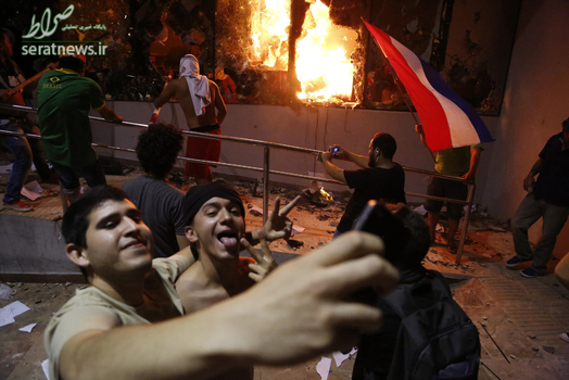 عکس سلفی مقابل ساختمان کنگره آتش گرفته پاراگوئه پس از اعتراض به موافقت سنای پاراگوئه با اعمال اصلاحاتی در قانون اساسی این کشور