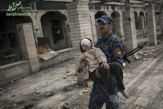 یک نظامی عراقی در حال حمل پسربچه مجروح شده در موصل