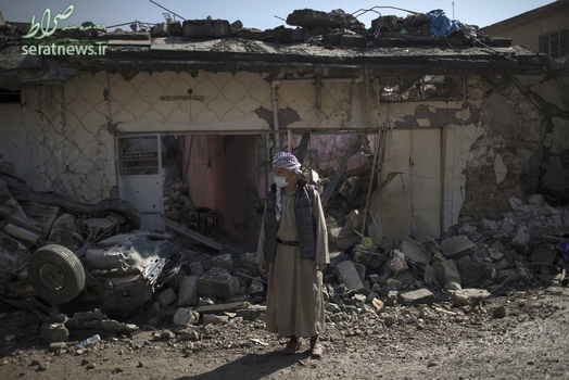 مردم موصلی با ماسک ایستاده مقابل خانه تخریب شده خود