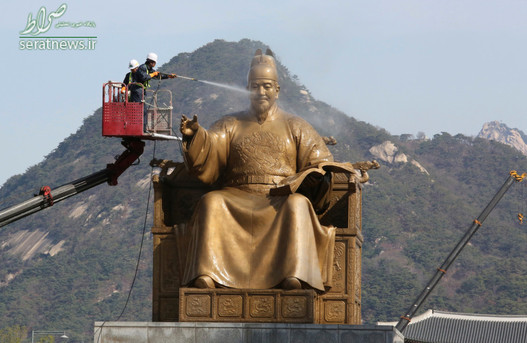 یک کارگر در حال شستشوی مجسمه شاه سجونگ در سئول کره جنوبی