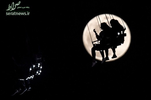 نمایی زیبا از دو زن سوار شده بر یک چرخ و فلک در مقابل ماه - فرانکفورت، آلمان