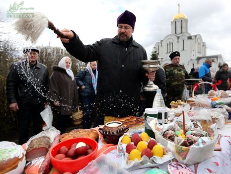 یک کشیش کلیسای ارتدوکس در حال متبرک کردن کیک و تخم مرغ های رنگی عید پاک در مینسک بلاروس