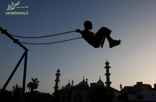 تاب بازی یک کودک در غروب در نزدیکی مسجدی در شهر کراچی پاکستان