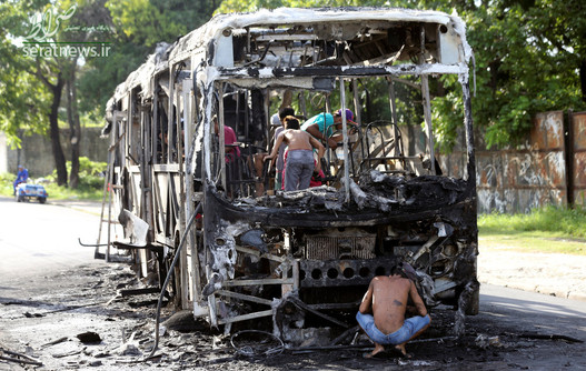 مردم در حال درآوردن وسایل سالم مانده یک اتوبوس سوخته در فورتالزا برزیل