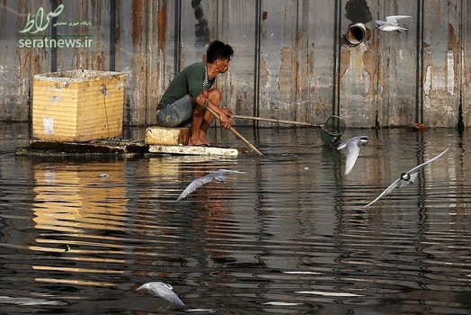 مردی در حال جمع آوری مواد قابل بازیافت از رودخانه ای در مانیل فیلیپین