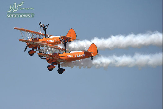 دو زن ایستاده روی دو هواپیما در طول برگزاری یک نمایش هوایی در استان هنان چین