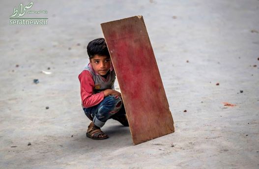 یک پسر بچه کشمیری برای در امان ماندن از تیررس نیروهای ارتش و امنیتی هند از یک تخته استفاده می کند