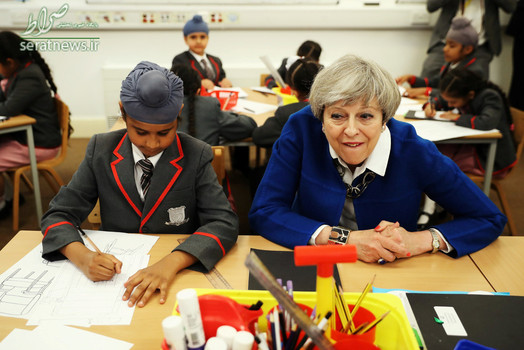 ترزا می نخست وزیر انگلیس نشسته در یک کلاس مدرسه ابتدایی در بیرمنگام
