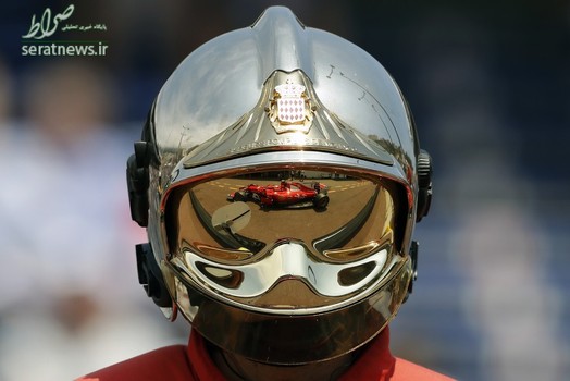 انعکاس تصویری از خودروی کیمی رایکونن راننده فراری بر روی کلاه ایمنی یک آتش نشان در مسابقات فرمول یک جایزه بزرگ موناکو