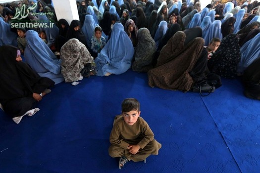 یک پسر نشسته در مقابل گروهی از زنان در صف دریافت جیره مواد غذایی ماه رمضان در هرات افغانستان
