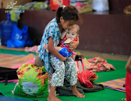 یک دختربچه با نوزادی در آغوش در انتظار رسیدن نیروهای امدادی برای تخلیه منطقه ای در فیلیپین