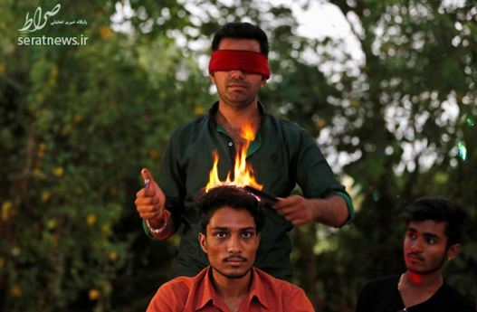 یک آرایشگر در احمدآباد هند با چشمان بسته و آتش موهای مشتریانش را اصلاح می کند