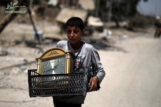 پسر آواره عراقی در حال حمل یک سبد و ساعت در غرب موصل