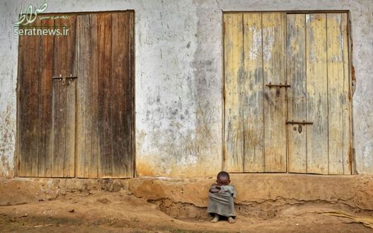 یک کودک اوگاندایی نشسته در مقابل خانه اش در حومه شهر ماساکا