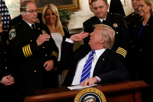 دست دادن دونالد ترامپ رییس جمهور آمریکا با یک مقام اف بی آی پیش از امضای یک لایحه در کاخ سفید