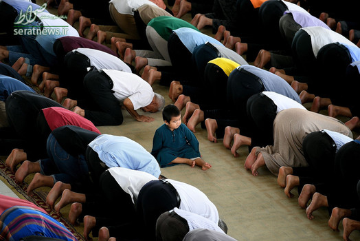 یک پسربچه نشسته در میان صفوف نمازگزاران در مسجدی در پوتراجایای مالزی