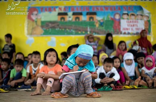 یک کودک پنج ساله در حال نوشتن بر روی نوت بوک در یک کلاس درس موقت - میندانائو، فیلیپین