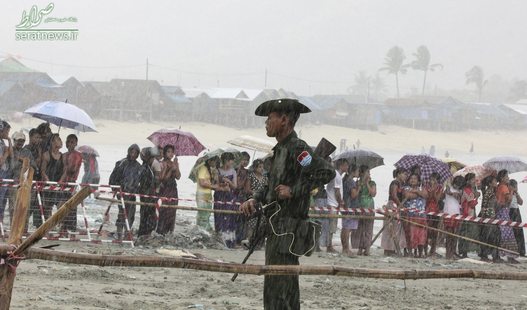 یک سرباز و دهها نفر از مردم میانمار در انتظار رسیدن اجساد یک هواپیمای سقوط کرده در دریا