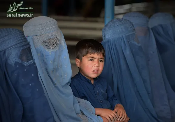 یک پسر افغان نشسته در میان چند زن مهاجر در کمیساریای عالی ملل متحد برای پناهندگان برای بازگشت به وطن - پیشاور، پاکستان